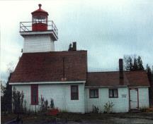 Vue du phare au détroit de Mississagi, où l'on peut apercevoir sa lanterne proéminente, et la maison attenante d’un étage, coiffée d’un toit à deux versants, avec un petit ajout.; Transport Canada / Transports Canada