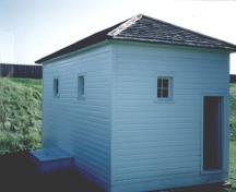 Vue du bâtiment des latrines, qui montre la disposition des portes et les petites fenêtres à quatre carreaux, 1992.; Agence Parcs Canada / Parks Canada Agency, 1992.