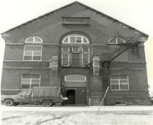 View of the front entrance of the Armoury, showing the construction of red smooth brick and stone, 1991.; Department of National Defence / Ministère de la Défense nationale, 1991.