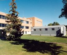 Vue de la façade latérale du bâtiment 84, où l'on peut apercevoir son toit plat, ses fenêtres en bandeau, et l’absence d’ornementation, 1996.; Department of National Defence / Ministère de la Défense nationale, 1996.