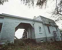 Vue générale du bâtiment 43, qui montre le passage couvert qui relie la résidence avec son toit en mansarde à la remise avec son toit à deux versants, vers 2004.; Parks Canada Agency / Agence Parcs Canada, circa / vers 2004.