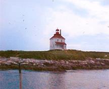 Panoramic view of Rook Island from the north demonstrating the building’s distinctive, isolated silhouette, which is visible from the mainland and all points in the harbour, reinforces the lighthouse's landmark and symbolic value to the community, 2001.; Department of Fisheries & Oceans Canada/Département de pêches et océans Canada, 2001.