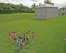 Corner view of the North Magazine with the clean and simple architectural treatment, including the regularity of the fenestration, which is consistent with the style evident in all of the buildings located around the parade ground, 2006.; Parks Canada Agency / Agence Parcs Canada, B. Aquin, 2006.