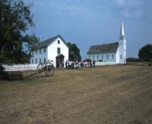 Panoramic view of Saint-Antoine de Padoue Rectory (left) and Church (right) showing their overall design and materials that harmonize with the historic setting, 2003.; Parks Canada Agency/Agence Parcs Canada, D. Venne., 2003.