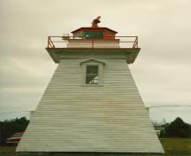 Façade latérale du Phare, qui montre le volume bas et carré et le profil du bâtiment qui consiste en un fût effilé complété par une galerie carrée en bois et une lanterne octogonale, 1990.; Canadian Coast Guard / Garde côtière canadienne, 1990.