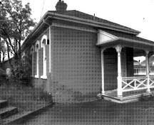 Vue de coin de l'élévation nord-est de l'édifice 29 démontrant la véranda avec boiseries décoratives et la main courante sur la façade principale, 1989.; Parks Canada Agency/Agence Parcs Canada, I. Doull, 1989.