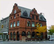 Vue générale de la Banque de Montréal  mettant de l'emphase sur le toit aigu et les rampants chantournés et sculptés des pignons et lucarnes;, 2004.; Parks Canada Agency / Agence Parcs Canada, 2004.