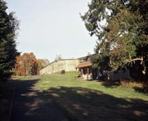 Vue de l'extérieur de la cantine du Fort Rodd Hill, montrant le porche incliné, avec ses chevrons apparents, le revêtement du toit et les cinq poteaux de bois chanfreinés, 2001.; Parks Canada Agency/Agence Parcs Canada, D. Mumford, 2001.