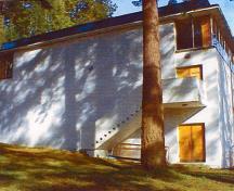 General view of the southern facade Swimming Pool RR22A showing the building's simple, horizontal cubic volumes emphasized by the smooth, white-concrete walls, flat roofs, and broad overhanging eaves, 2000.; Department of National Defence / Ministère de la Défense nationale, 2000.