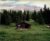 Vue de l'entrée principale du chalet de patrouille des gardes du parc de Byng, qui montre le porche ouvert, en rondins, munis de supports pour les pannes de la ferme et des poteaux à l’extrémité du pignon, 1997.; Parks Canada Agency / Agence Parcs Canada, 1997.