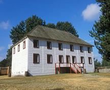 Corner view of the Big House showing its formally arranged windows and elevated entry doors and its whitewashed exterior, 2005.; Parks Canada Agency / Agence Parcs Canada, J. Gordon, 2005.
