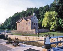 Vue générale du Bâtiment de l'intendance mettant de l'emphase sur sa situation imposante dans la vallée du Colonel-By, face au canal Rideau et en surplomb de son entrée nord, 2002.; Parks Canada Agency / Agence Parcs Canada, A. Guindon, 2002.