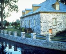 Vue de l'extérieur du bâtiment, qui montre le volume rectangulaire d'un étage sous un toit en croupe.; Parks Canada Agency / Agence Parcs Canada.