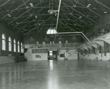 Vue de l'intérieur du manège militaire, qui montre le grand volume sans appui intermédiaire de la salle d’exercices, créé par l’emploi de fermes Polonceau exposées, 1990.; Department of National Defence / Ministère de la Défense nationale, 1990.