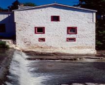 Vue latérale du moulin Légaré, qui montre ses murs épais avec de petites fenêtres, 1999.; Parks Canada Agency / Agence Parcs Canada, 1999.