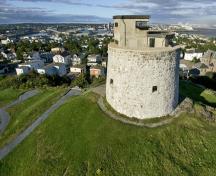Vue générale de la tour Martello de Carleton, qui montre son implantation sur une hauteur rocheuse escarpée offrant une vue directe sur le centre-ville de Saint-Jean.; Parks Canada Agency / Agence Parcs Canada.