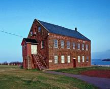 Vue générale de la Banque des fermiers de Rustico qui montre la construction en pierres de grès posées régulièrement par assise.; Parks Canada Agency / Agence Parcs Canada.