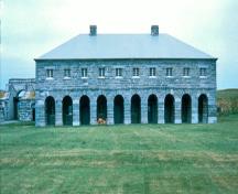 General view of Fort Lennox showing the buildings, their stone construction, their volume, mass, roof type, window and door placements.; Parks Canada Agency / Agence Parcs Canada.