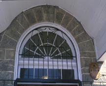 Vue détaillée de l'ancien hangar d'exercices d'Elora, qui montre l'oeil de boeuf situé au dessus de l'entrée centrale, 1995.; Parks Canada Agency / Agence Parcs Canada, J. Butterill, 1995.