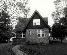 Façade of the Superintendant's Residence, showing the gable-ended extension to the front, faced with vertical wooden siding, ca. 1990.; Parks Canada Agency / Agence Parcs Canada, c./v.1990.