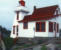 Vue générale du Phare, qui montre la tour carrée et tronconique, la lanterne hexagonale, le balcon de la tour, la construction en bois et la résidence intégrée du gardien.; Agence Parcs Canada / Parks Canada Agency.