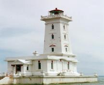 Vue en angle du Phare de la Point Abino, qui montre sa colonne carrée effilée de cinq étages s'élevant d'un piédestal ouvragé d'un étage de haut, orné de décorations d'inspiration classique, 1997.; Parks Canada Agency /Agence Parcs Canada, A. Powter, 1997.