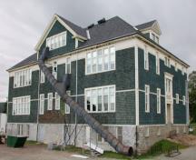 This corner view of the building illustrates the cut stone foundation and the stained wood shingles punctuated by wood trim window surrounds and corner boards.; PNB 2005