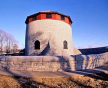 Vue générale de la tour Murney montrant la masse ronde et compacte de la tour, avec son toit conique et un dense réseau de caponnières, ainsi que son caractère symétrique, la circonférence de la tour étant égale à sa hauteur.; Parks Canada Agency/ Agence Parcs Canada, J. Butterill, 1994.