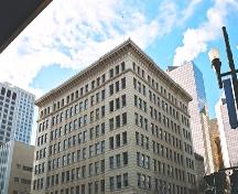 This image illustrates the view of the McLeod Building from the northeast showing the upper part of the two main, terracotta-clad facades. The large overhanging terracotta cornice caps the bulding on two sides. (2004); City of Edmonton, 2004