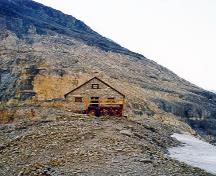 Vue générale du refuge du Col Abbot, qui montre son environnement pittoresque dans un col montagneux éloigné et dénudé.; Parks Canada Agency / Agence Parcs Canada.