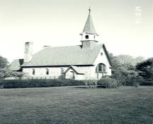 Vue latérale de la Chapelle commémorative, montrant le clocher qui se dresse sur le toit immédiatement derrière l’entrée principale et le toit à pente raide, couvert de cuivre et présentant des égouts retroussés, 1991.; Canadian Parks Service, Atlantic Regional Office/ Service canadien des parcs, Bureau régional de l'Atlantique, 1991.