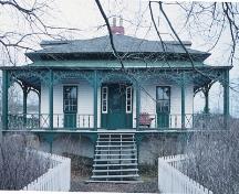 Vue de l'entrée montrant le côté pittoresque de la maison de style «cottage orné», avec sa masse carrée sous un toit en croupe orné de lucarnes.; Parks Canada Agency / Agence Parcs Canada