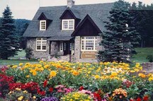 Façade of the Visitor Information Centre East, showing the central entrance porch created by the extension of the roof over the entrance, the three-bay front façade, and the gable-ended extension to the front, 1987.; Parks Canada Agency / Agence Parcs Canada, 1987.