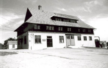 Vue générale de la Grange des céréales, montrant ses murs extérieurs qui sont revêtus de parement de planches avec couvre-joints au niveau du rez-de-chaussée et de bardeaux de bois au-dessus, 1983.; Parks Canada Agency / Agence Parcs Canada, 1983