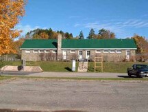 View of the exterior of the Bathhouse, showing the vernacular detailing, characterized by the multi-paned, deeply recessed sash windows, arranged in a regular rhythm.; Parks Canada Agency / Agence Parcs Canada.
