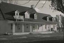 View of Governors' Cottage, showing its verandah with columns and the small, second-floor balcony, 1973.; Agence Parcs Canada / Parks Canada Agency, 1973.