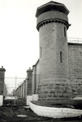 View of one of the Towers from inside the walls, showing the circular frame guardhouse, glazed on all sides, with a steep octagonal roof, 1990.; Parks Canada Agency / Agence Parcs Canada, Dana Johnson, 1990.