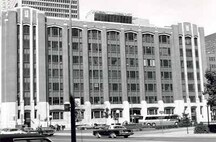 Vue de la façade de l'édifice fédéral, qui montre l’emploi de tympans de métal entre chacune des larges fenêtres pour créer une unité visuelle entre les piliers par une série de panneaux allongés, 1978.; Parks Canada Agency / Agence Parcs Canada, 1978.