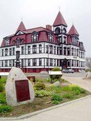 General view of the former Lunenburg Academy, showing the mansard roof in the French Empire style with segmental dormer windows, massive central chimney, and the three projecting towers with pyramidal roofs.; Parks Canada | Parcs Canada