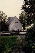 Façade de la maison des Français, qui montre le volume sur un étage et demi construit à ras le sol, avec quelques fenêtres, 1991.; Parks Canada Agency / Agence Parcs Canada, Christine Chartré, 1991.