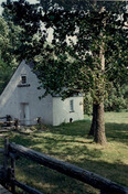 Vue en angle de la maison des Français, qui montre la construction en pierre avec les murs extérieurs revêtus de crépi, 1991.; Parks Canada Agency / Agence Parcs Canada, Christine Chartré, 1991.