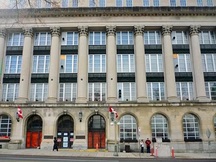 View of the main facade of the Wellington Building emphasizing the use of quality finish materials on the exterior, including the smooth Indiana limestone cladding with granite base and the bronze grilles and spandrel panels, 2011.; Parks Canada | Parcs Canada, M. Therrien, 2011.